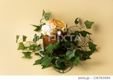Traditional glazed Easter cake with decorative green leaves, minimalist composition on peach colored background Traditional glazed Easter cake with decorative green leaves, minimalist composition on peach colored background 136763094