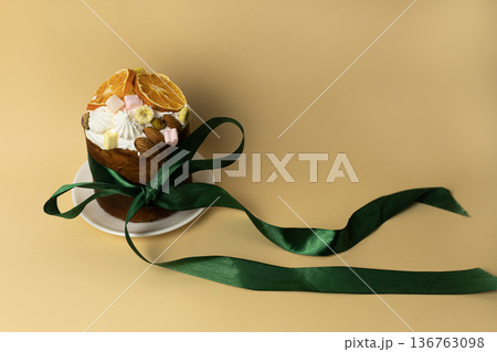 Spring holiday Easter cake garnished with almonds, marshmallows and orange slices on white plate with elegant dark green satin ribbon Spring holiday Easter cake garnished with almonds, marshmallows and orange slices on white plate with elegant dark green satin ribbon 136763098