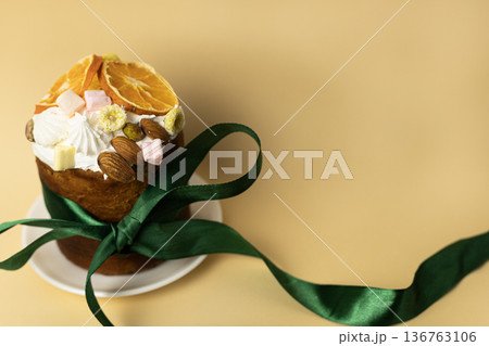 Glazed Easter bread with almond topping and citrus wedges on white dish, accented with deep green ribbon, festive composition Glazed Easter bread with almond topping and citrus wedges on white dish, accented with deep green ribbon, festive composition 136763106