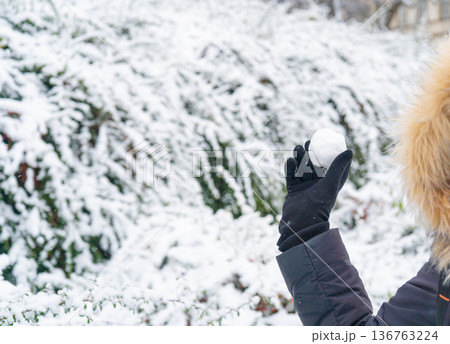 Snowball in hand, snowfall in the city. Outdoor family games in winter, climate change concept 136763224