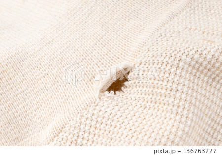 Torn fabric with a hole close-up. Damaged textiles background, old rip cotton material 136763227