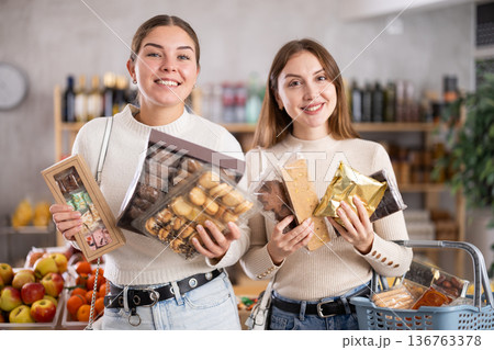 Two girls in store while shopping, choose sweets and chat sweetly Two girls in store while shopping, choose sweets and chat sweetly 136763378