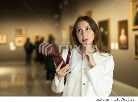 Woman with mobile phone on the background of paintings Woman with mobile phone on the background of paintings 136763515