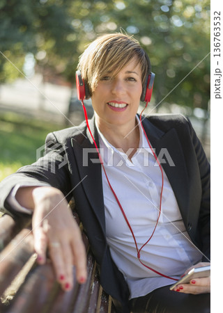 Smiling businesswoman with red headphones outdoors 136763532