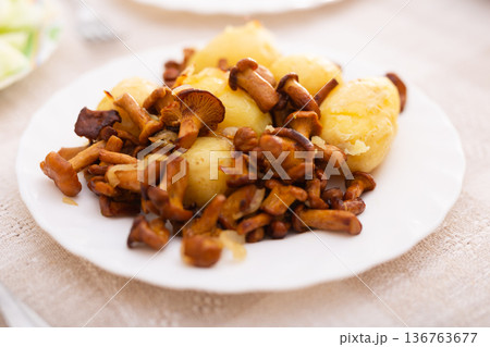 fried chanterelles with new potatoes on a white plate 136763677