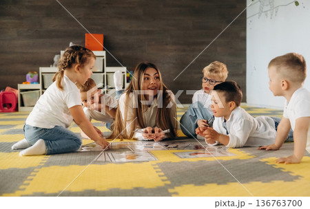 Gathered on the floor, learning. Children in kindergarten with their teacher Gathered on the floor, learning. Children in kindergarten with their teacher 136763700