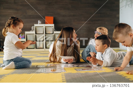 Gathered on the floor, learning. Children in kindergarten with their teacher Gathered on the floor, learning. Children in kindergarten with their teacher 136763701