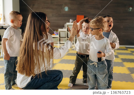 Lesson is over, high five. Children in kindergarten with their teacher 136763723