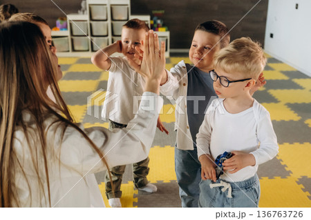 Lesson is over, high five. Children in kindergarten with their teacher Lesson is over, high five. Children in kindergarten with their teacher 136763726
