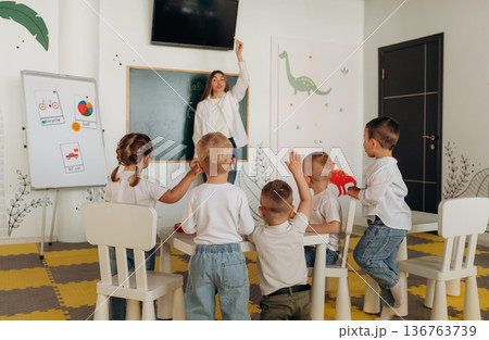 Socialization and education. Children in kindergarten with their teacher Socialization and education. Children in kindergarten with their teacher 136763739