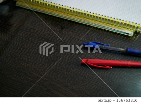 Teenage Boy Doing Homework At Cozy Home Desk With Notebook And Pens In Evening Teenage Boy Doing Homework At Cozy Home Desk With Notebook And Pens In Evening 136763810