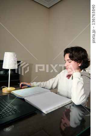 Teenage Boy Doing Homework In The Evening At Cozy Home Interior Teenage Boy Doing Homework In The Evening At Cozy Home Interior 136763840