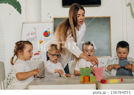 Colorful toys, educational game. Children in kindergarten with their teacher Colorful toys, educational game. Children in kindergarten with their teacher 136764053