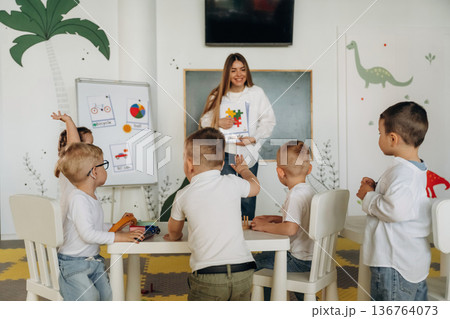 Having fun by learning. Children in kindergarten with their teacher Having fun by learning. Children in kindergarten with their teacher 136764073