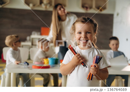 The pencils are in hands. Children in kindergarten with their teacher The pencils are in hands. Children in kindergarten with their teacher 136764089