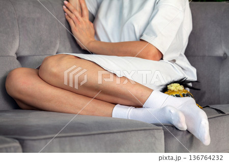 Close-up of the legs of a woman in white socks on the couch 136764232