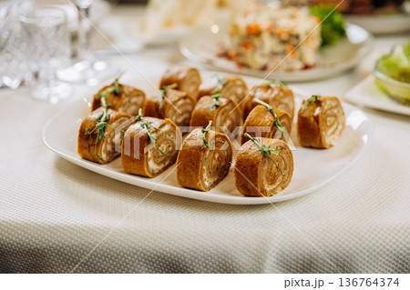 Savory stuffed pancake rolls served as festive appetizer on banquet table 136764374