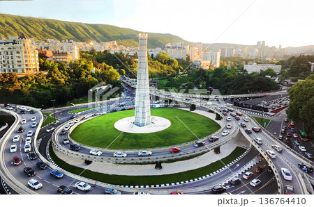 Aerial view on Tbilisi with Kura river and skyscrapers (maybe hotels) an and traffic on embankments . Greenery in May with fantastic plane trees 136764410