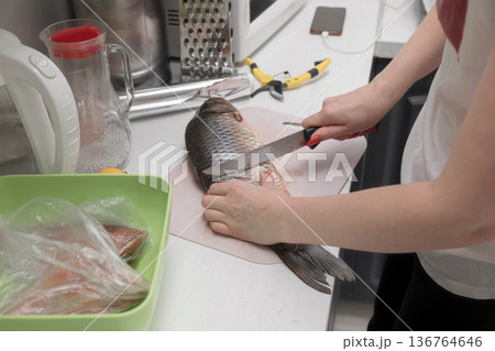 Housewife preparing food at the kitchen, cutting fresh fish 136764646