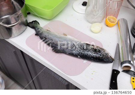 Fish and knife on a kitchen table Fish and knife on a kitchen table 136764650