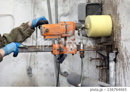 Worker using an electric drill to make a hole in a concrete wall, closeup 136764665