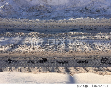 Winter road showing vehicle tire tracks in snow and slush 136764894