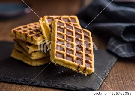 Sweet waffles with chocolate on wooden table. Sweet waffles with chocolate on wooden table. 136765083