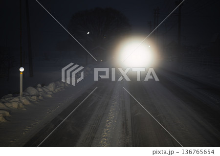 早朝の暗い雪道と対向車のヘッドライト：冬の運転の視界不良と危険性 136765654