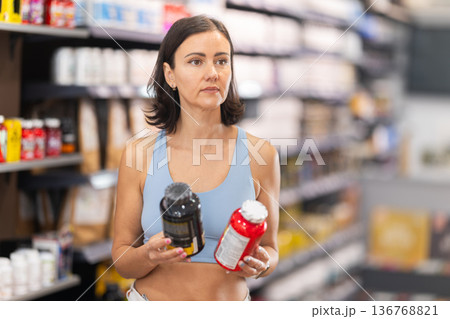 Woman chooses protein sports nutrition in store Woman chooses protein sports nutrition in store 136768821