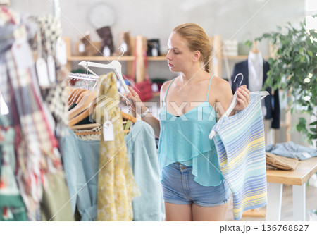 Teenage girl choosing top in clothing store Teenage girl choosing top in clothing store 136768827