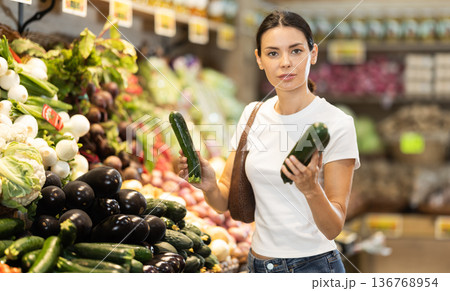 Young woman shopping in vegetable store and buy zucchini 136768954