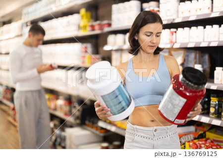 Woman chooses protein sports nutrition in store 136769125