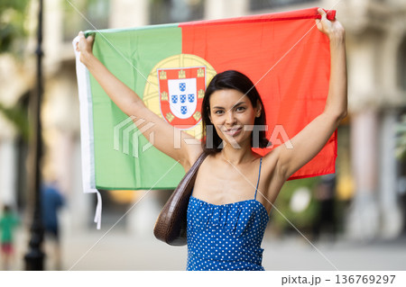 Young woman with portuguese flag on city street 136769297