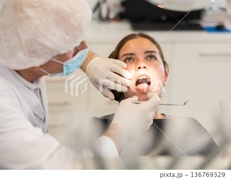 Elderly male dentist examining female patient 136769329