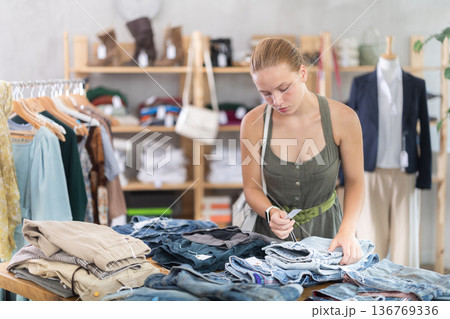 Teenage girl choosing pantaloons in clothing store 136769336