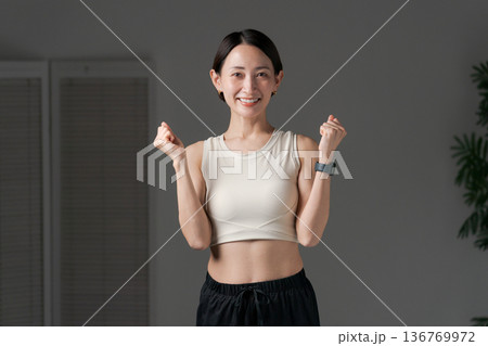 ガッツポーズをするトレーニングウェアの女性 136769972