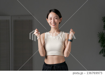 ガッツポーズをするトレーニングウェアの女性 136769973
