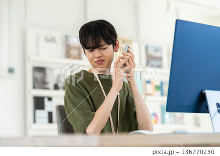 オフィスでクレームの電話を受ける若い男性 136770230