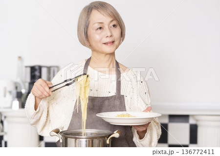 キッチンでパスタを茹でるシニア女性 136772411
