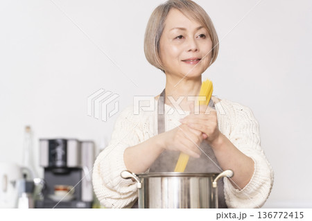 キッチンでパスタを茹でるシニア女性 キッチンでパスタを茹でるシニア女性 136772415