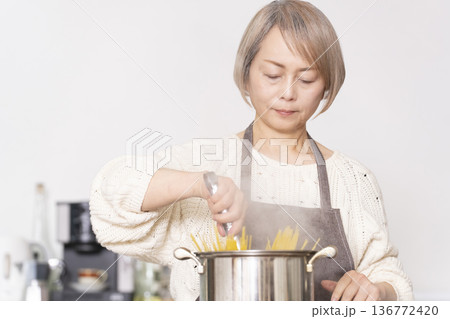 キッチンでパスタを茹でるシニア女性 キッチンでパスタを茹でるシニア女性 136772420