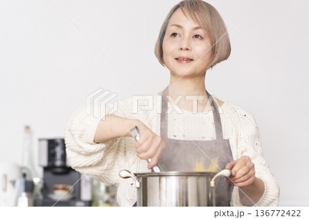 キッチンでパスタを茹でるシニア女性 キッチンでパスタを茹でるシニア女性 136772422
