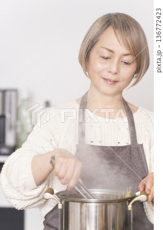 キッチンでパスタを茹でるシニア女性 キッチンでパスタを茹でるシニア女性 136772423