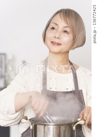キッチンでパスタを茹でるシニア女性 キッチンでパスタを茹でるシニア女性 136772425