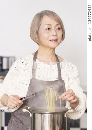 キッチンでパスタを茹でるシニア女性 136772433