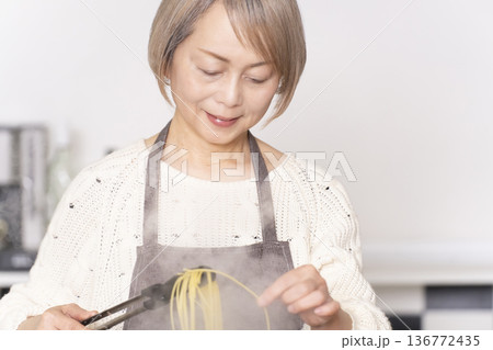 キッチンでパスタを茹でるシニア女性 キッチンでパスタを茹でるシニア女性 136772435