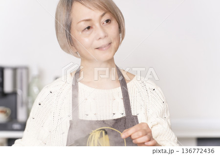 キッチンでパスタを茹でるシニア女性 キッチンでパスタを茹でるシニア女性 136772436