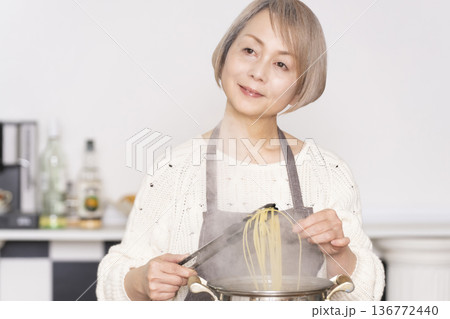 キッチンでパスタを茹でるシニア女性 キッチンでパスタを茹でるシニア女性 136772440