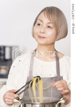 キッチンでパスタを茹でるシニア女性 キッチンでパスタを茹でるシニア女性 136772443