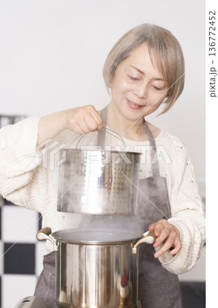 キッチンでパスタを茹でるシニア女性 136772452